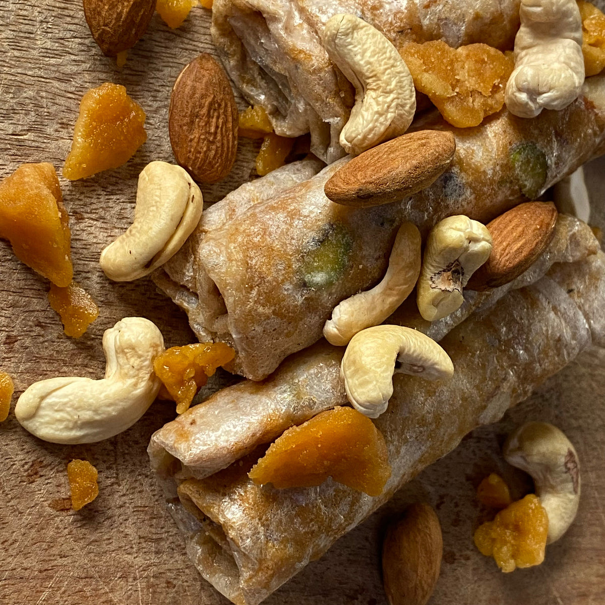 Close-up of Jaggery Kaju Badam Papersweet pieces with scattered cashews, almonds and jaggery chunks