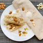 Close-up top view of Sugar Dry Fruit Cashew Almond Pistachio Papersweet rolls garnished with almonds, cashews and pistachios, with sugar and dry fruits scattered alongside